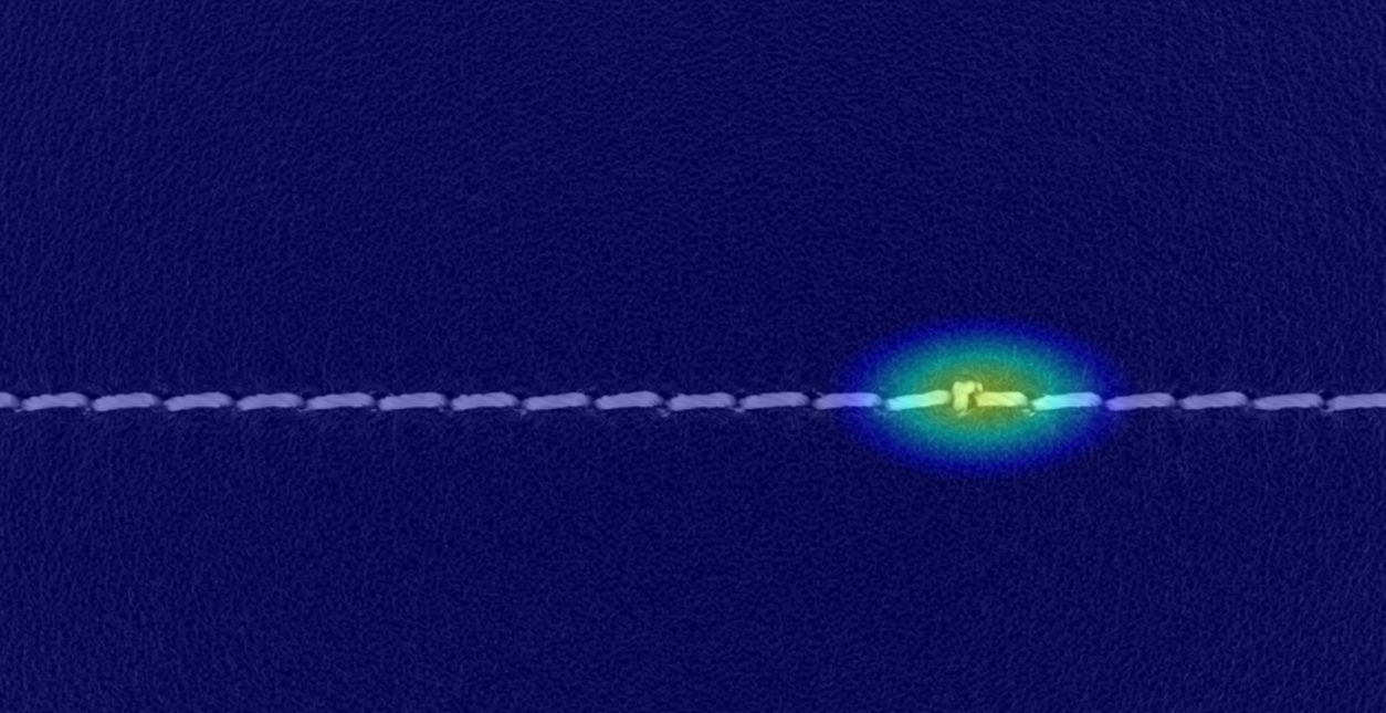 An illustration of defect detection in sewing showing the anomalous area highlighted in bright colour.