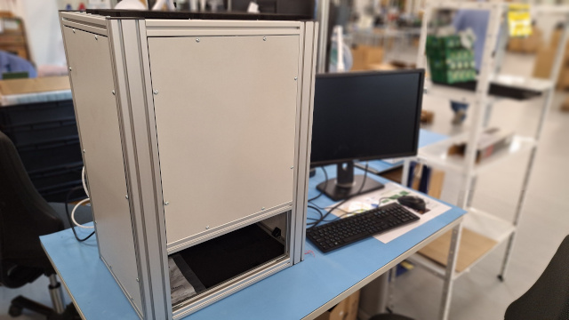 Установка за визуална инспекция на печатни платки, заедно с компютърна система, разположени на работна маса в производствена среда.